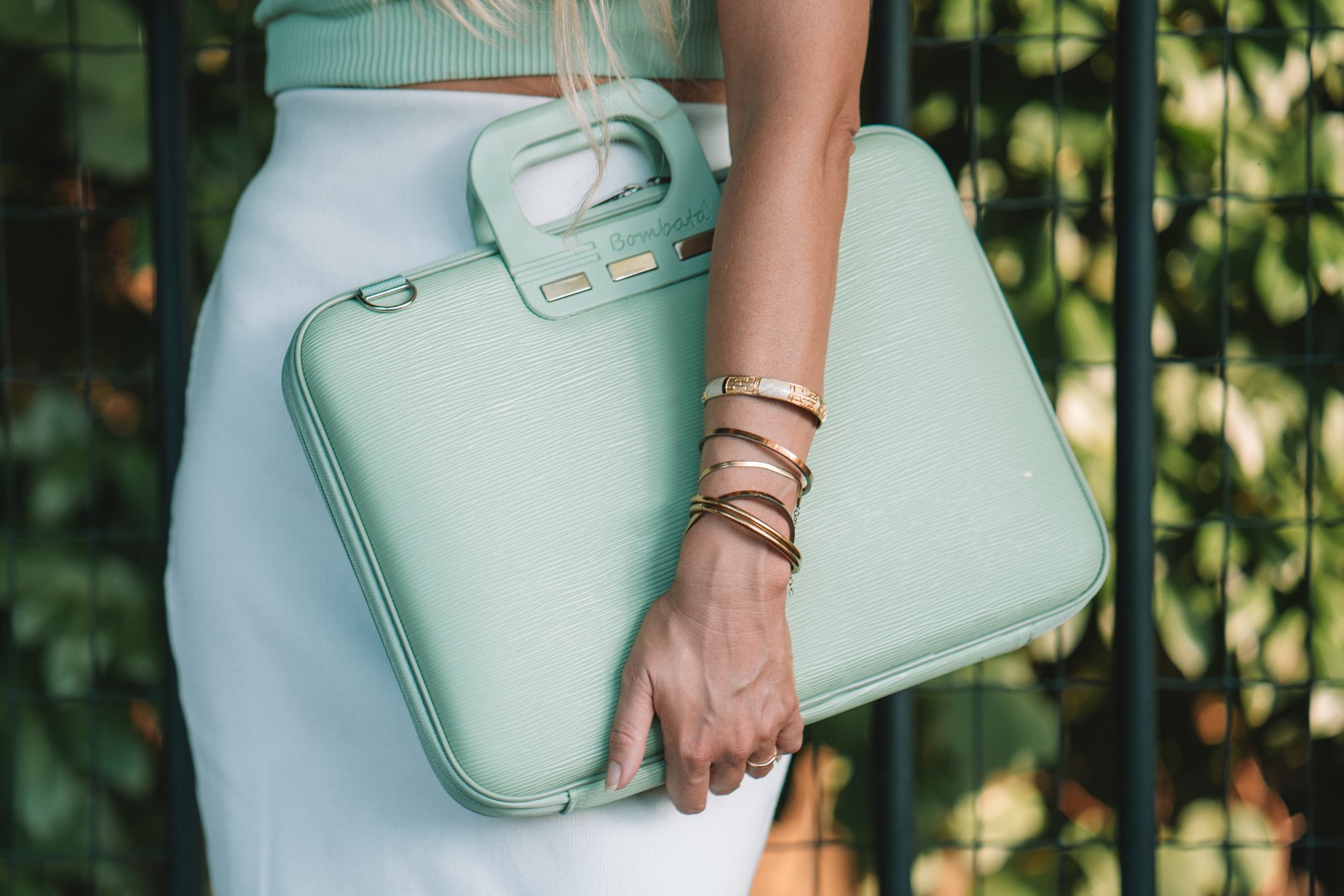 a person holding a mint green briefcase